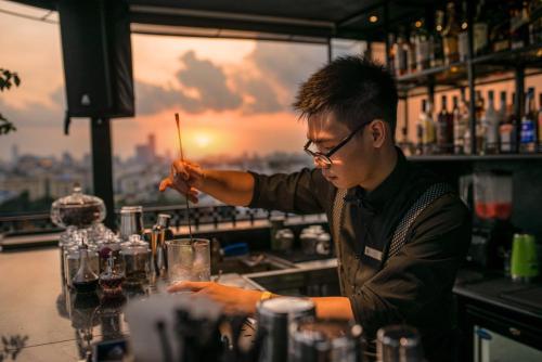 a man making a drink at a bar at La Nueva Boutique Hotel Hanoi & Spa in Hanoi