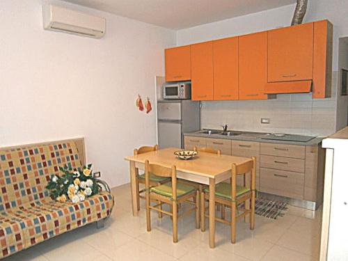 eine Küche mit einem Tisch, Stühlen und einem Sofa in der Unterkunft Jolly in Bibione