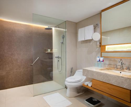 a bathroom with a shower and a toilet and a sink at Hotel Santika Premiere Slipi Jakarta in Jakarta