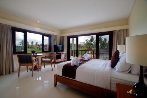 una camera con un grande letto, una scrivania e sedie di DLobong Suite Ubud ad Ubud