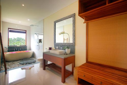bagno con vasca, lavandino e specchio di DLobong Suite Ubud ad Ubud