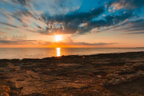a sunset on a rocky beach with the ocean at Torre Cintola Greenblu Sea Emotions in Monopoli