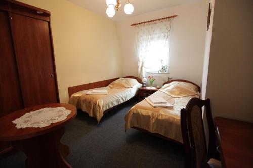 a room with two beds and a table and a window at Hotel Kaukaska in Wolsztyn