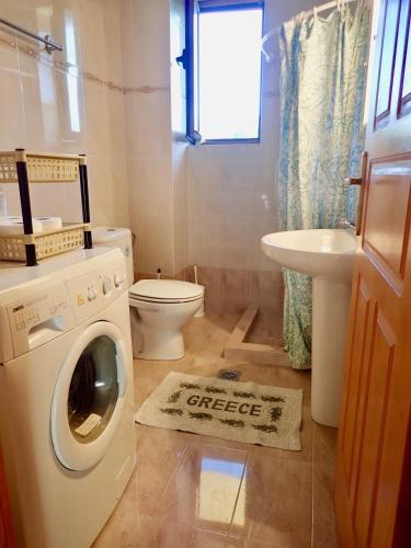 a bathroom with a washing machine and a toilet at Marika's House in Alónai