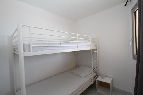 カネ・アン・ルシヨンにあるCOPACABANA - 3 pièces vue mer avec piscine et parkingの白い部屋の白い二段ベッド