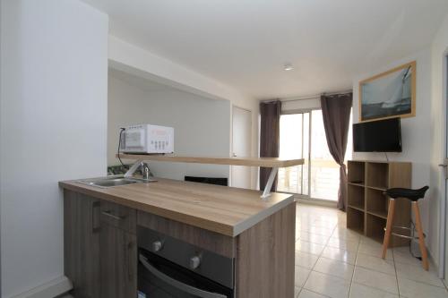 Il comprend une cuisine équipée d'un évier et d'un comptoir avec un four micro-ondes. dans l'établissement COPACABANA - 3 pièces vue mer avec piscine et parking, à Canet