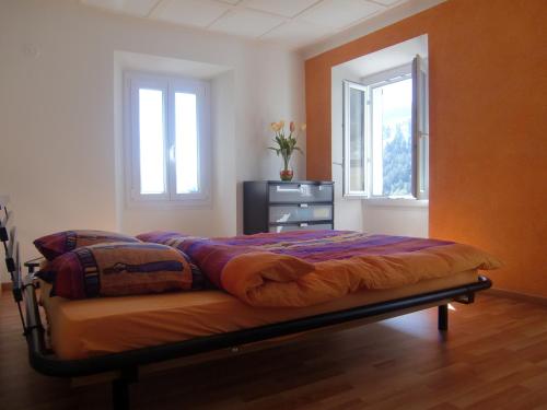 a bed in a bedroom with two windows at Appartamento via Luina in Airolo