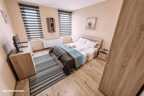 a bedroom with a bed and a flat screen tv at Brickyard Apartments Cluj in Cluj-Napoca