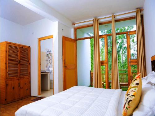 a bedroom with a white bed and a large window at Hundar Resort in Hundar