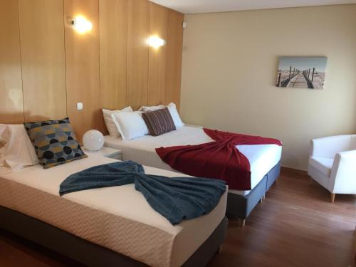 ein Hotelzimmer mit 2 Betten und einem Stuhl in der Unterkunft Villa Jackson in Vilamoura