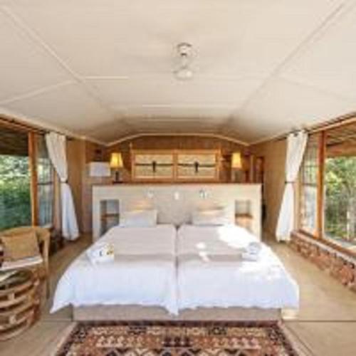 a bedroom with a white bed in a room with windows at Waterberg Guest Farm in Waterberg National Park