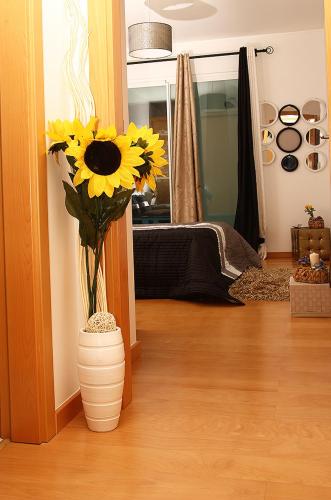 a vase filled with sunflowers in a room at Sunny Little Sister Apartment - 7 min walking from the sea in Machico