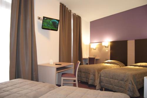 Cette chambre comprend deux lits, un bureau et une télévision. dans l'établissement Hôtel Roc de Massabielle, à Lourdes