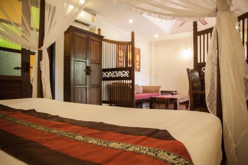 a bedroom with a bed and a living room at Baan Orapin in Chiang Mai