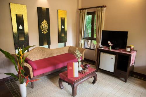 a living room with a couch and a tv at Baan Orapin in Chiang Mai