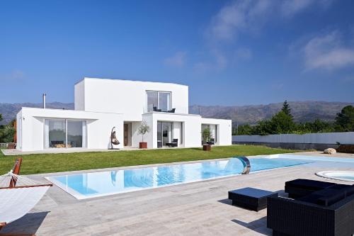 a white house with a swimming pool in front of it at Oliveira House in Castelo Novo