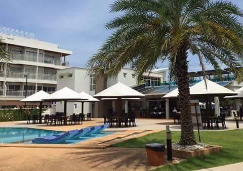 a resort with a palm tree and tables and umbrellas at Grandblue Condo 410 in Mae Pim