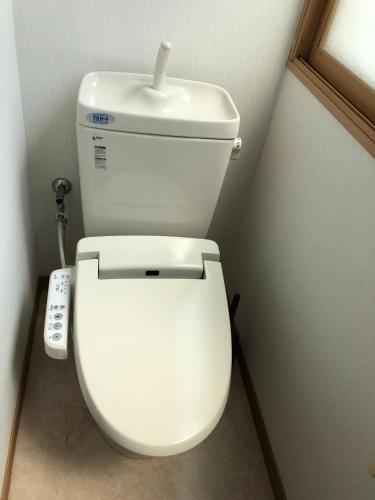 a white toilet in a bathroom with a remote control at Kurashiki Base Inarimachi in Kurashiki