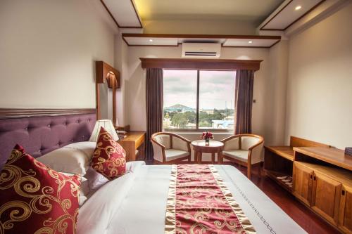 a hotel room with a bed and a window at Sakura Princess Hotel in Mandalay