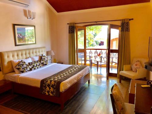 sypialnia z łóżkiem i drzwiami prowadzącymi na patio w obiekcie The Bungalows Light House, Goa by Leisure Hotels w mieście Candolim