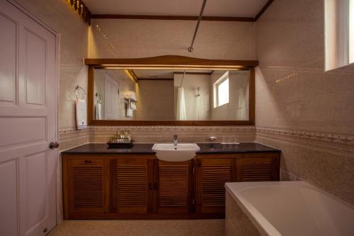 a bathroom with a sink and a mirror and a tub at Sakura Princess Hotel in Mandalay
