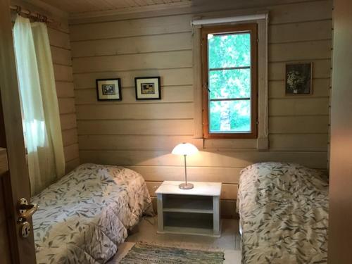 1 dormitorio con 2 camas y mesa con lámpara en Ylä-Saarikko Holiday Cottages, en Kuusa