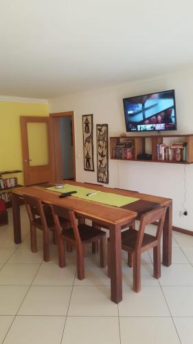 a wooden table with benches in a room with a tv at Suite Mariposa Sospesa Sul Mare in Mindelo