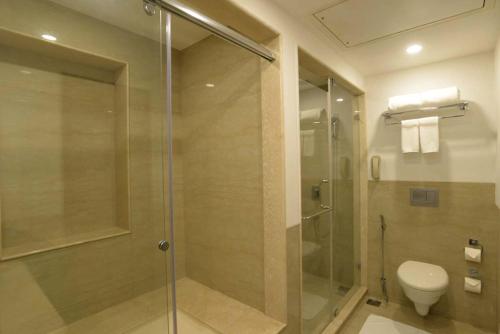 a bathroom with a glass shower and a toilet at Lemon Tree Hotel Coimbatore in Coimbatore