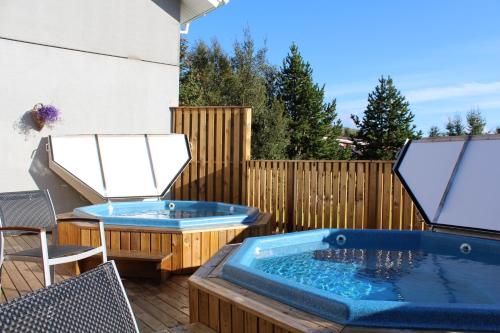 two hot tubs on a patio with a fence at Hótel Eyvindará in Egilsstadir
