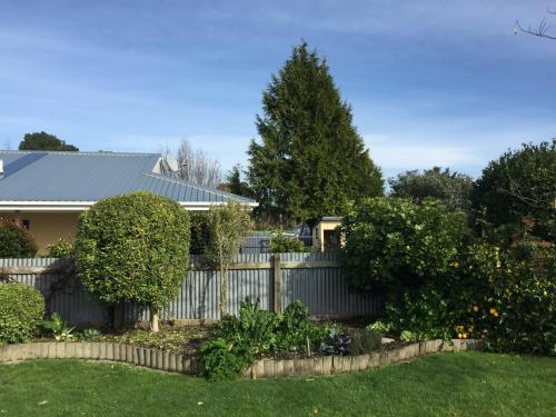 a fence in front of a house with a yard at Cosy, Central Greytown Sleepout in Greytown