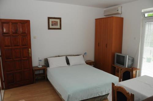 a bedroom with two beds and a tv in it at Apartments Dragišić in Sveti Stefan