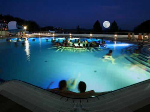 a group of people in a swimming pool at night at Thermenhof PuchasPLUS Loipersdorf in Jennersdorf