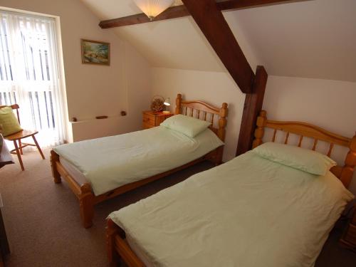 a bedroom with two beds and a window at Jacobs Barn in Lifton