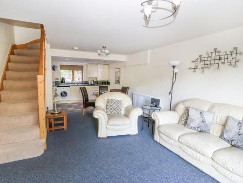 a living room with two white couches and a staircase at Hove Wood View in Hebden Bridge