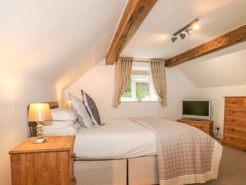 1 dormitorio con 1 cama grande y TV en Farley Cottage I en Oakamoor