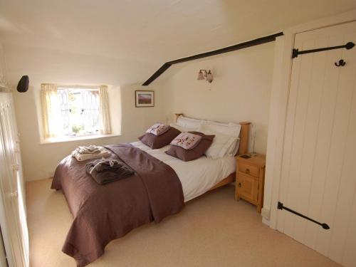 a bedroom with a large bed and a window at Appletree Cottage in Ilsington