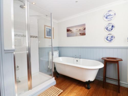 a white bath tub in a bathroom with a glass shower at The Old School House in Bala