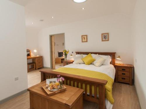 ein Schlafzimmer mit einem großen Bett und einem Tisch in der Unterkunft Fritillary Cottage in Bradworthy