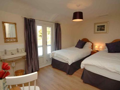 a bedroom with two beds and a sink and a window at Old Lyn Cottage in Lynmouth