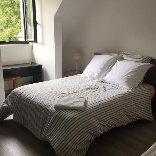 une chambre avec un grand lit avec des draps et des oreillers blancs dans l'établissement Cheng, à Saint-Germain-en-Laye