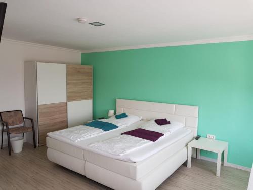 a bedroom with a white bed and a blue wall at Gaststätte und Hotel zur Krone in Pohlheim