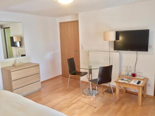 a room with a table and two chairs and a television at Hotel garni Königslinde - Wandern, Radeln, Skifahren & Genießen in Bayrischzell