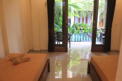 a room with two beds and doors to a courtyard at Donald Home Stay in Ubud