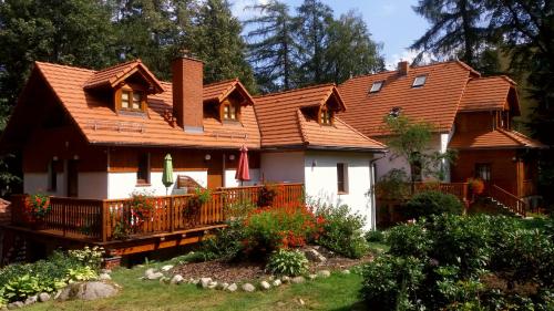 a house with a wooden roof and a yard at Dom Natury in Karpacz