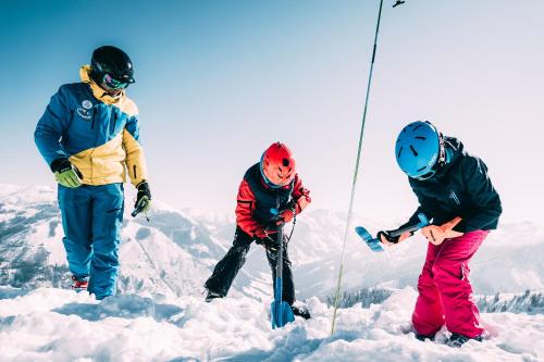 three people standing on top of a snow covered mountain at Kinderhotel Stegerhof in Donnersbachwald