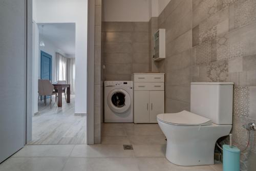 a bathroom with a toilet and a washing machine at Gina's Cozy House in Kamilari