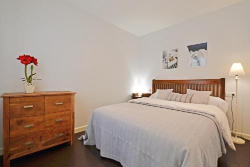 a bedroom with a bed and a dresser with a flower on it at Ático con terraza en el centro de Alicante in Alicante