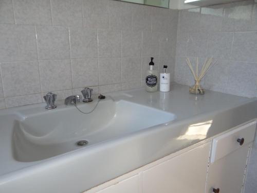 a white sink with two bottles on top of it at CREDO Guest House in Bloemfontein