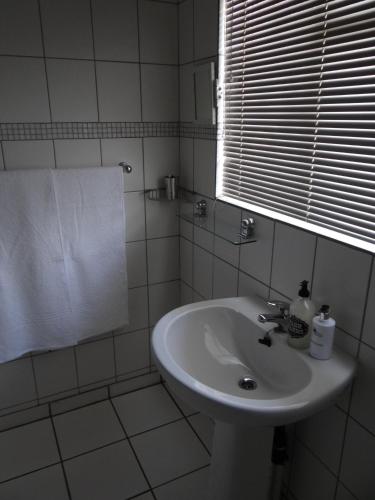 a white bathroom with a sink and a window at CREDO Guest House in Bloemfontein