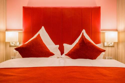 a bedroom with a red headboard and a bed with pillows at Best Western Plus Hotel Regence in Aachen